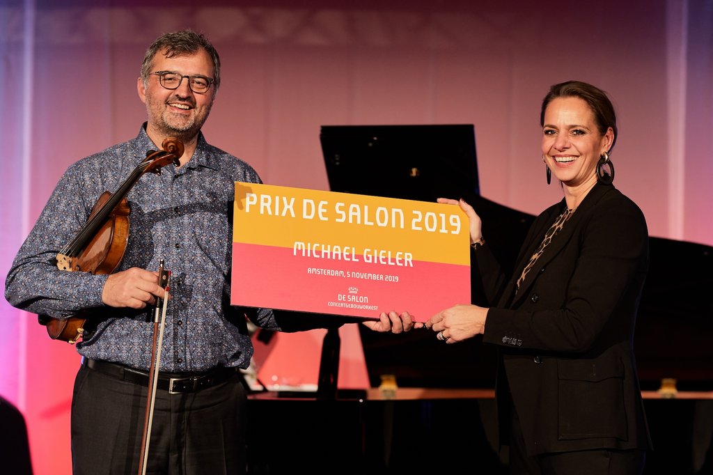 Michael Gieler (altviool) ontvangt dePrix de Salon 2019 op kantoor bij TMF Group. V.l.n.r. soloaltviolist Michael Gieler en Anne Christin Erbe, hoofd development