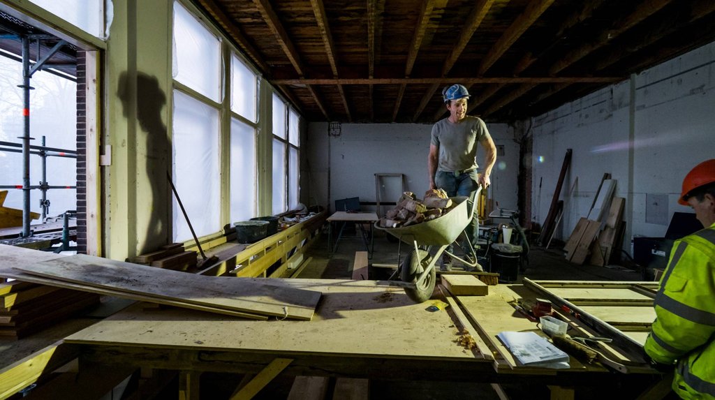 Puin wordt tijdens de verbouwing afgevoerd met een kruiwagen. Nu zetelt hier de artistieke directie.